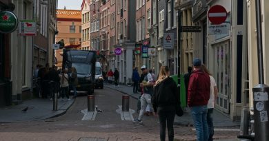 a group of people walking down a street next to tall buildings