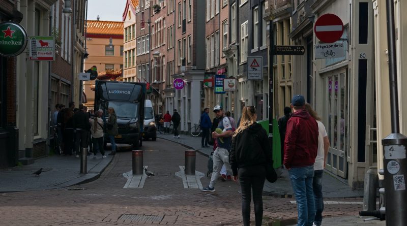 a group of people walking down a street next to tall buildings