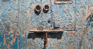 a rusted metal door with two knobs on it