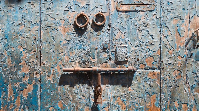 a rusted metal door with two knobs on it
