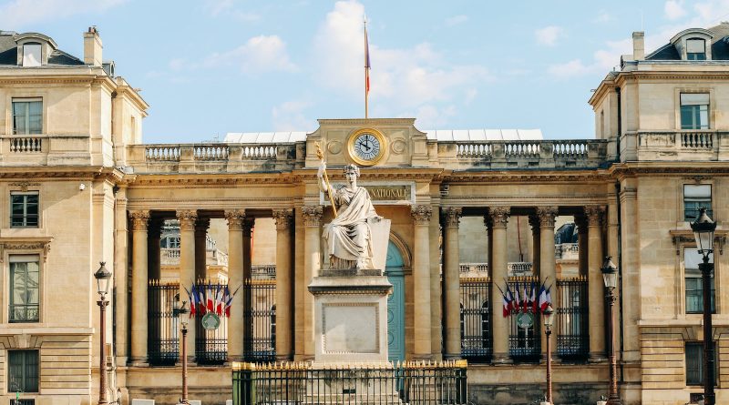 white concrete building with statue under white clouds during daytime